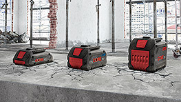 콘크리트 바닥에 빨간 강조가 있는 세 개의 검은색 Bosch Professional 배터리.