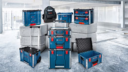 여러 개의 파란색 Bosch Professional 공구 상자가 빨간색 강조와 함께 콘크리트 바닥 위에 놓여 있습니다. 배경에는 검은색 배낭이 보입니다. 상자는 크기가 다르고 정리된 작업장 환경을 나타내기 위해 배열되어 있습니다.