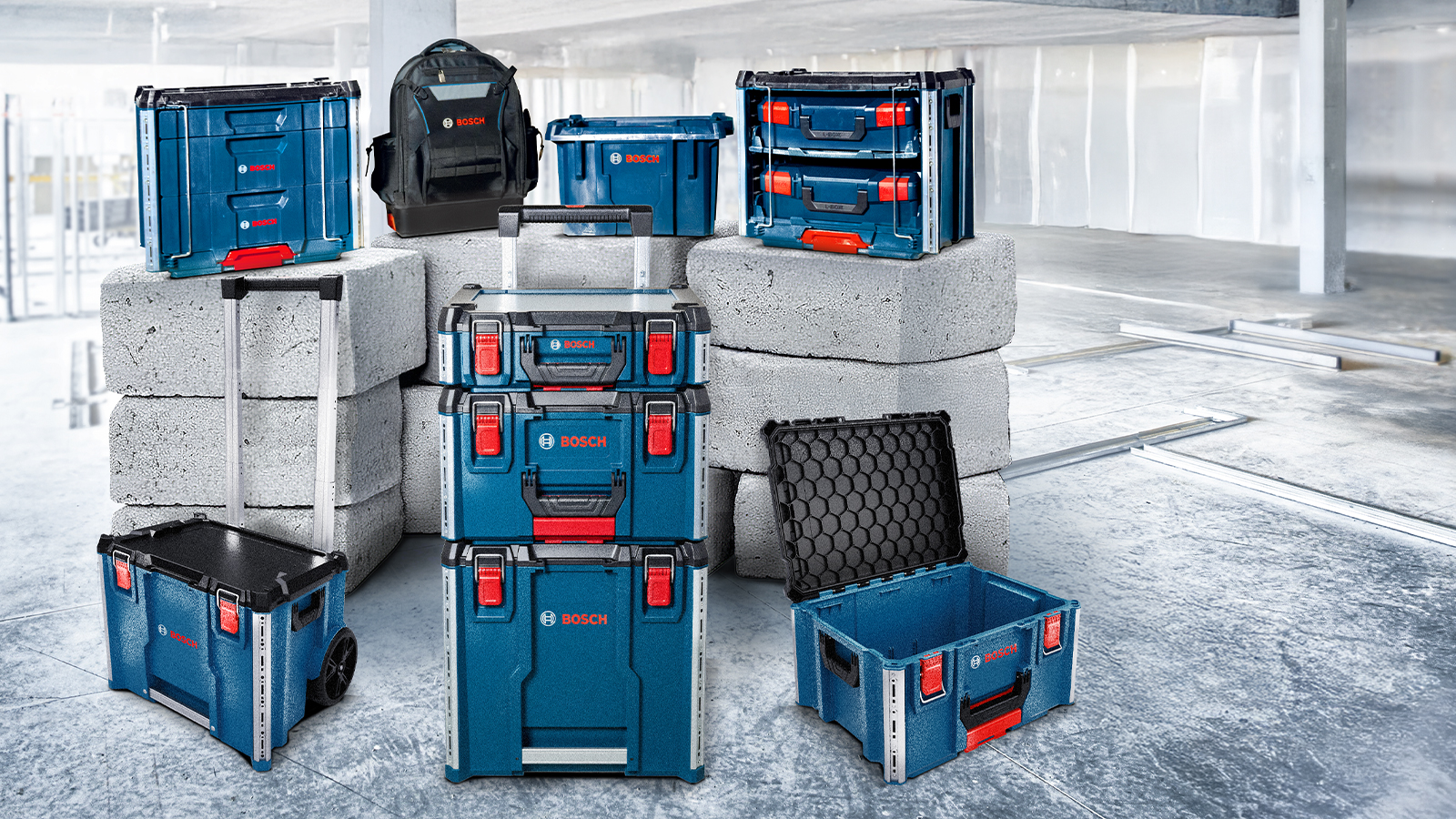 파란색과 검은색의 다양한 Bosch Professional 공구 상자가 현대적인 공간의 회색 콘크리트 블록 위에 놓여 있습니다.