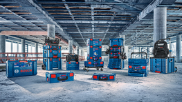 여러 개의 파란색 Bosch Professional 공구 상자가 건설 환경의 콘크리트 바닥에 놓여 있습니다.