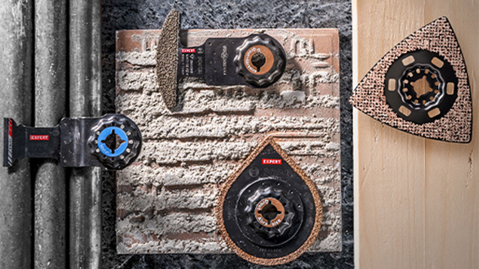 거친 표면에 있는 세 개의 Bosch Expert 도구와 파이프.