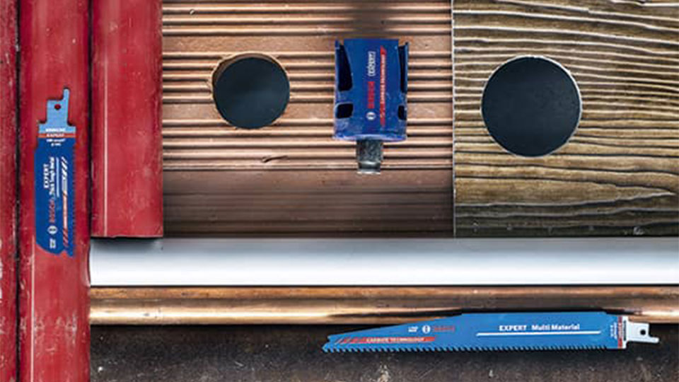 보쉬 프로페셔널 톱날이 나무 판자와 파이프 위에 놓여 있습니다.