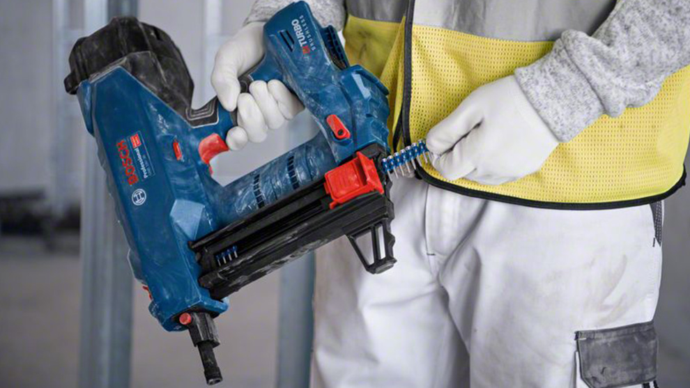 파란색 Bosch Professional 배터리 못 박는 기계가 한 사람에 의해 들려 있습니다.