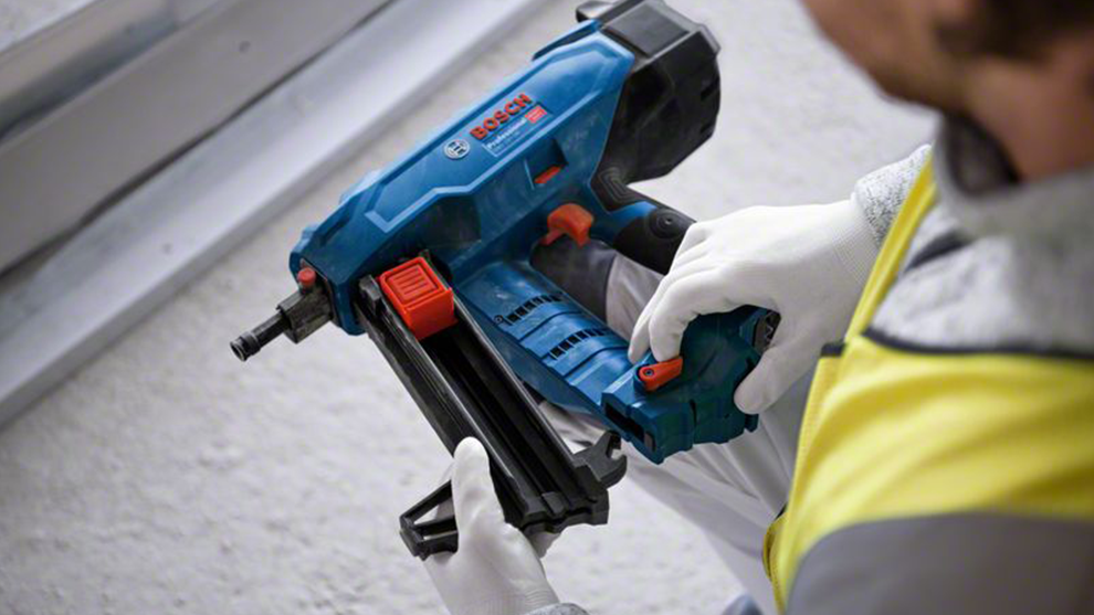 파란색 Bosch Professional 배터리 못 박는 기계가 한 사람에 의해 들려 있습니다.