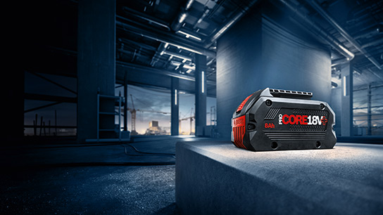 18V 시스템 특장점 건설 현장의 회색 콘크리트 블록 위에 검은색 Bosch Professional 배터리.