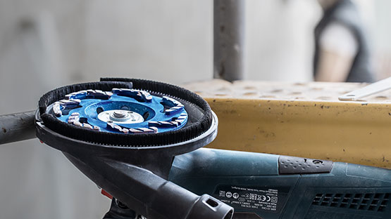 파란색 Bosch Professional 연마 부착물이 도구 위에 놓여 있습니다.