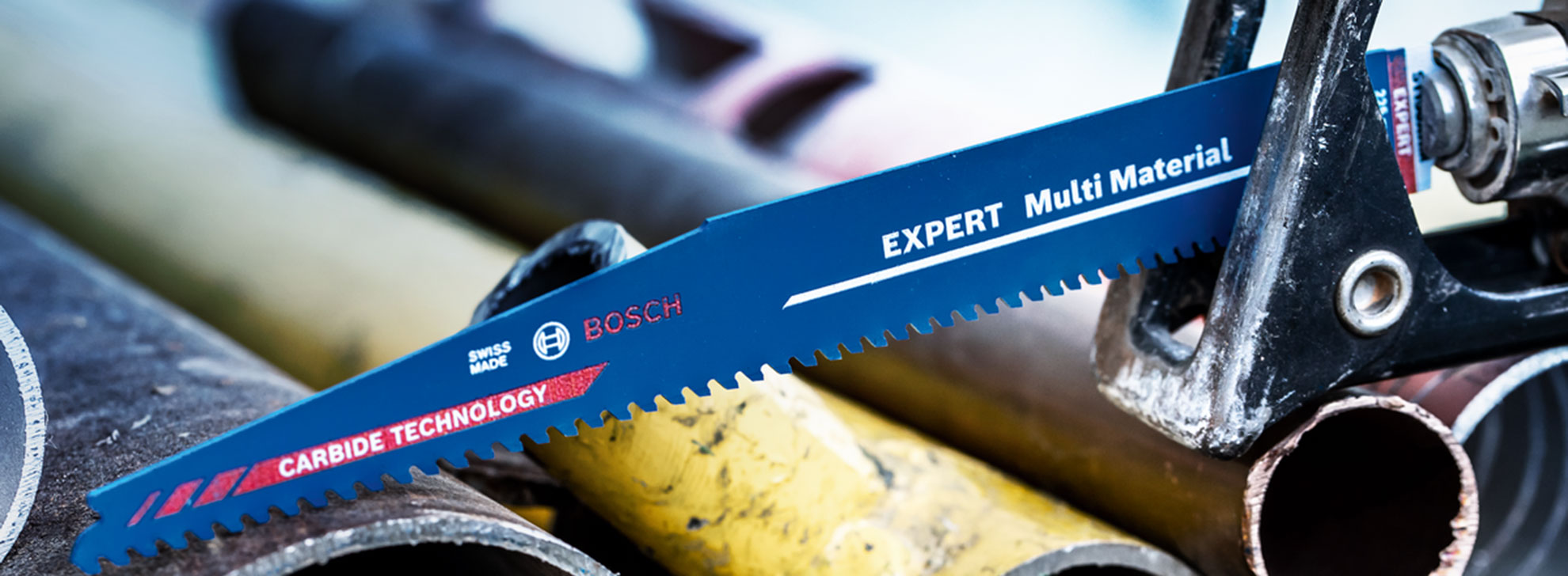 파란색 Bosch Expert 톱이 작업장에서 금속 파이프 위에 놓여 있습니다.