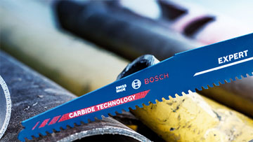 파란색 Bosch Expert 톱이 금속 및 플라스틱 파이프 위에 놓여 있습니다.