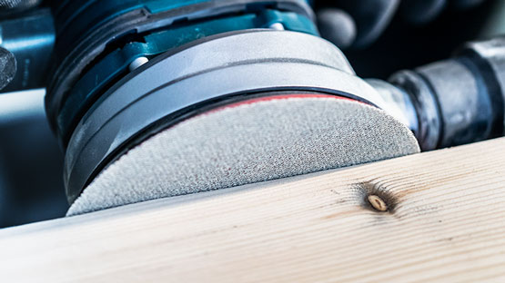 보쉬 프로페셔널 오르빗 샌더가 나무 판자를 작업하고 있습니다.