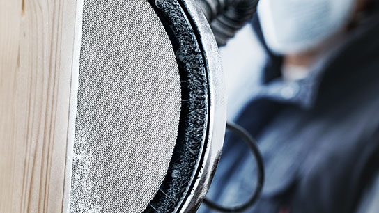 은색 그릴과 나무 표면이 있는 스피커의 클로즈업.