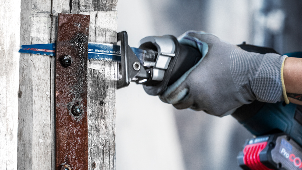 회색 장갑을 낀 손이 Bosch Professional 톱을 들고 있습니다.