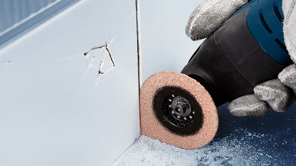 보쉬 프로페셔널 도구가 균열이 있는 벽을 연마하고 있습니다.