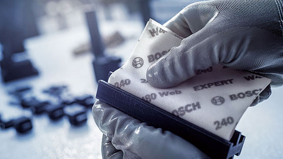 장갑을 낀 사람이 Bosch Expert의 사포를 들고 있습니다.