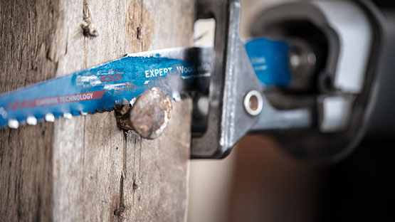 파란색 Bosch Expert 목재 톱이 나무 조각을 자르고 있습니다.