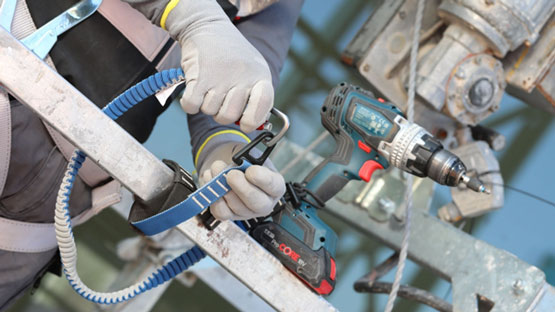 한 장인이 사다리 위에서 Bosch Professional 무선 드릴을 들고 있습니다.