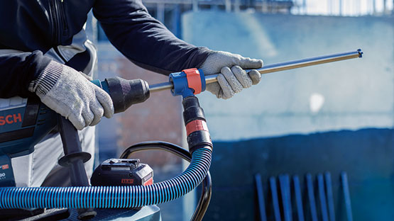 작업자가 손에 호스를 들고 Bosch Professional 드릴을 들고 있습니다.