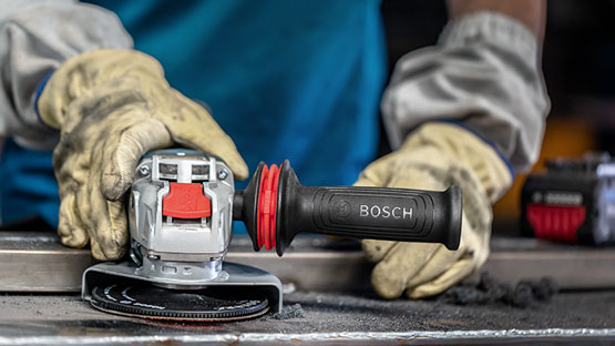 보쉬 프로페셔널 앵글 그라인더가 장갑을 낀 손에 의해 잡히고 있습니다.