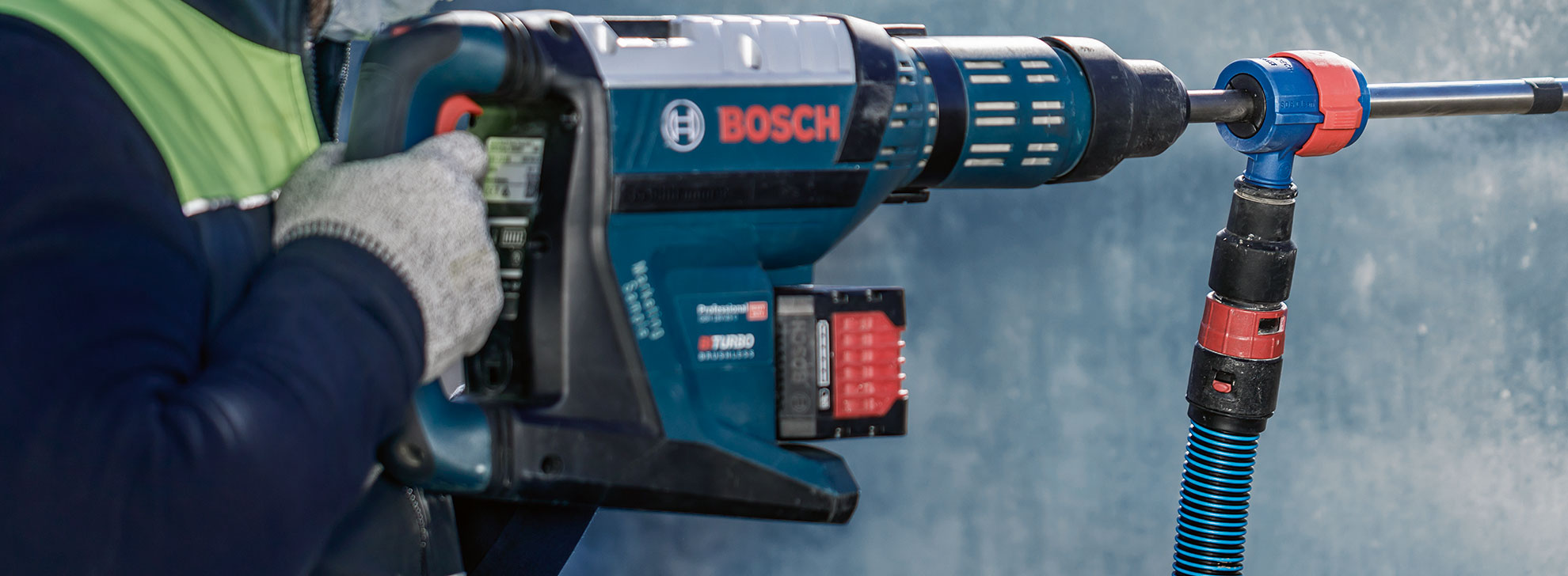 파란색 보쉬 프로페셔널 드릴이 장갑을 낀 사람이 들고 있습니다.