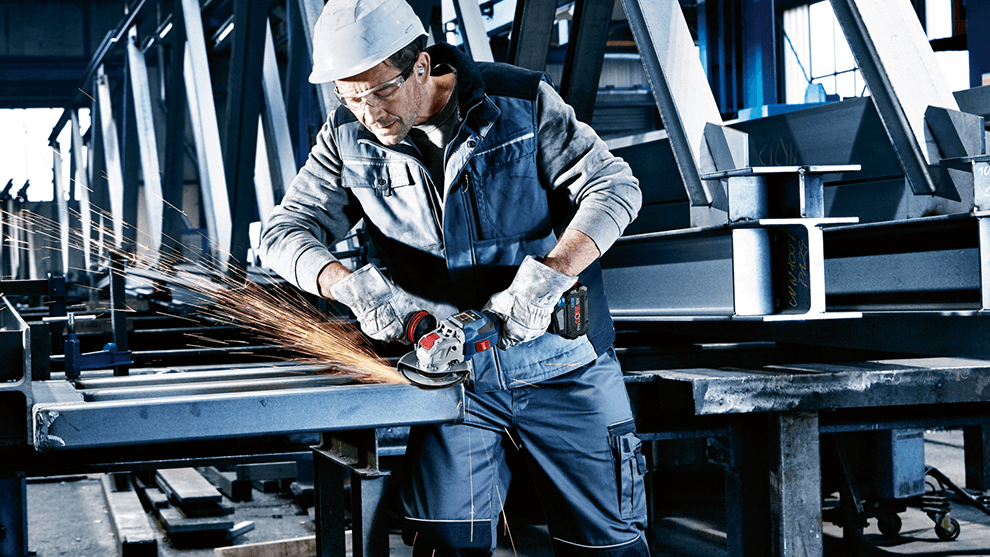 보쉬 앵글 그라인더를 사용하는 작업자가 작업장에서 금속 부품을 가공하고 있습니다.