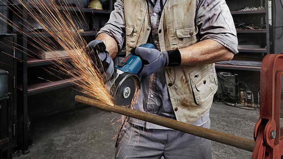 장인이 보쉬 도구로 나무 조각을 자르고 있습니다.