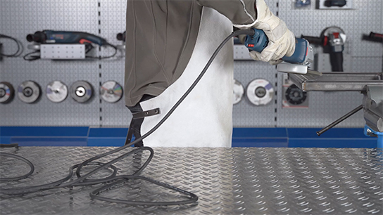 장인이 금속 표면에서 Bosch Professional 기계를 사용하고 있습니다.