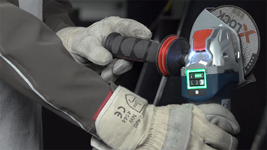 장인이 디스플레이가 있는 Bosch Professional 각도 그라인더를 사용하고 있습니다.