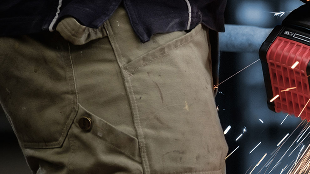 장인이 용접하고 있으며, 빨간 Bosch 도구에서 불꽃이 튀고 있습니다.