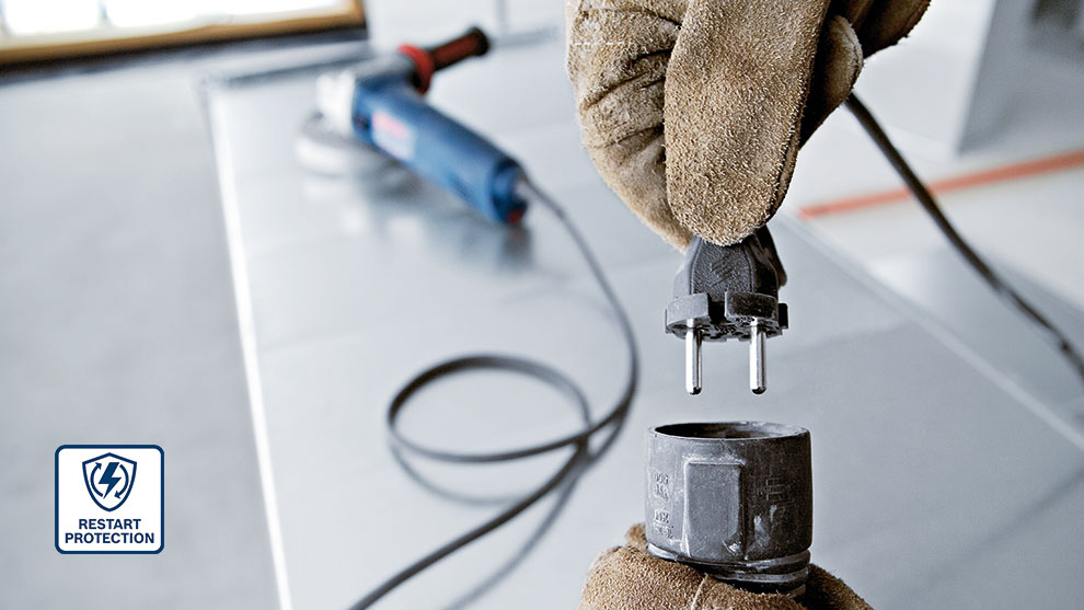 장갑을 낀 손이 콘센트 위에 플러그를 들고 있습니다.