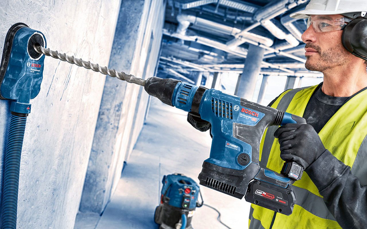 벽에 파란색 Bosch Professional 드릴을 가진 장인.