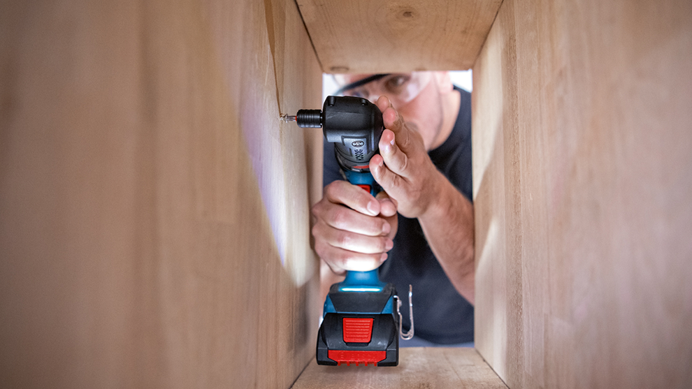 장인이 나무 프레임에서 Bosch Professional 무선 드릴을 사용하고 있습니다.