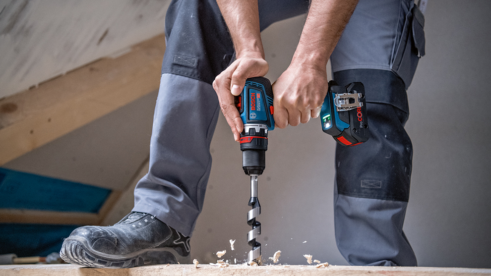 장인이 나무에 보쉬 프로페셔널 무선 드릴을 사용하고 있습니다.