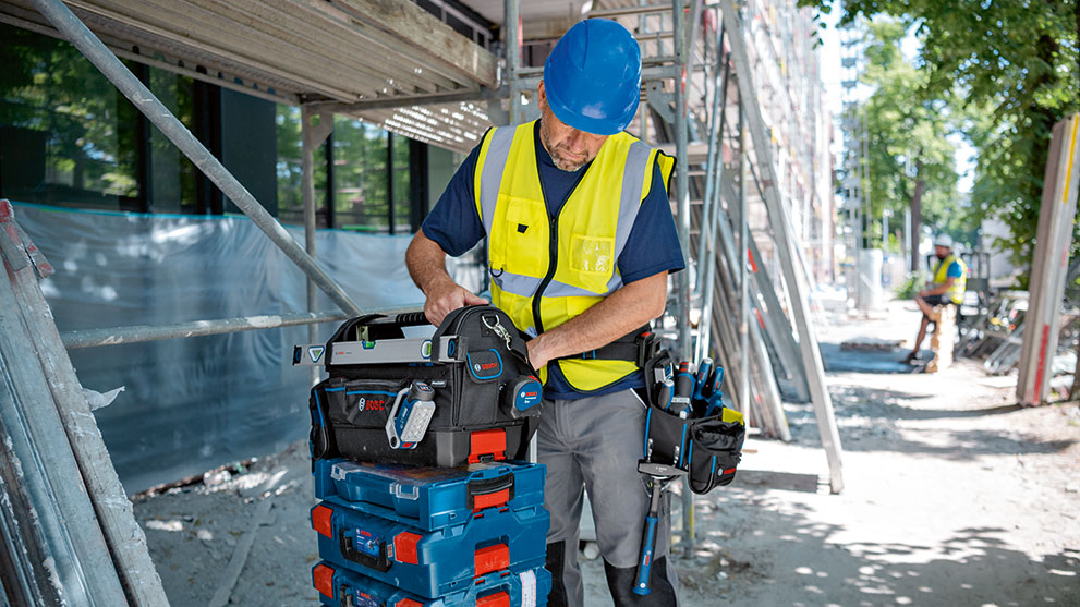 파란 헬멧을 쓴 건설 노동자가 Bosch 공구 상자에서 작업하고 있습니다.