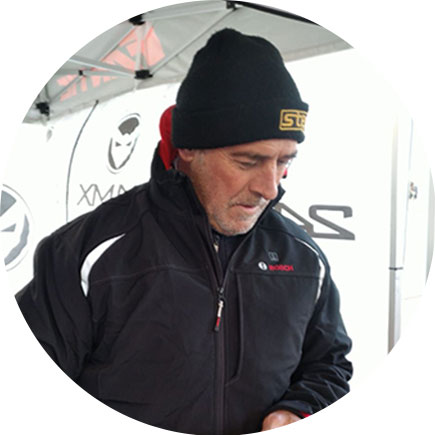 검은 재킷과 모자를 쓴 남자가 텐트 아래에 서 있습니다.