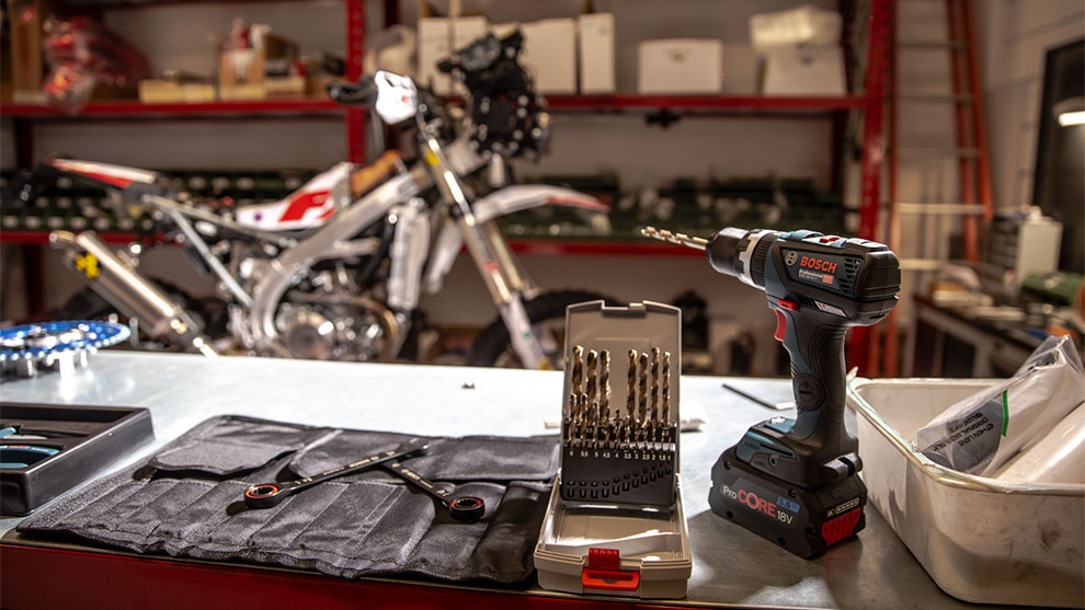 보쉬 프로페셔널 무선 드라이버가 도구 옆에 있는 테이블 위에 서 있습니다.