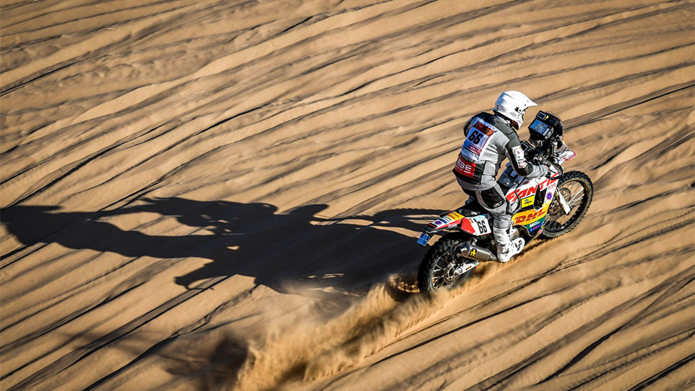 모래 위의 오토바이 운전사, 자국을 남기고, 태양이 긴 그림자를 드리웁니다.