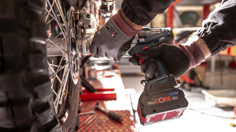 장인이 오토바이 타이어에 Bosch Professional 무선 드라이버를 사용하고 있습니다.