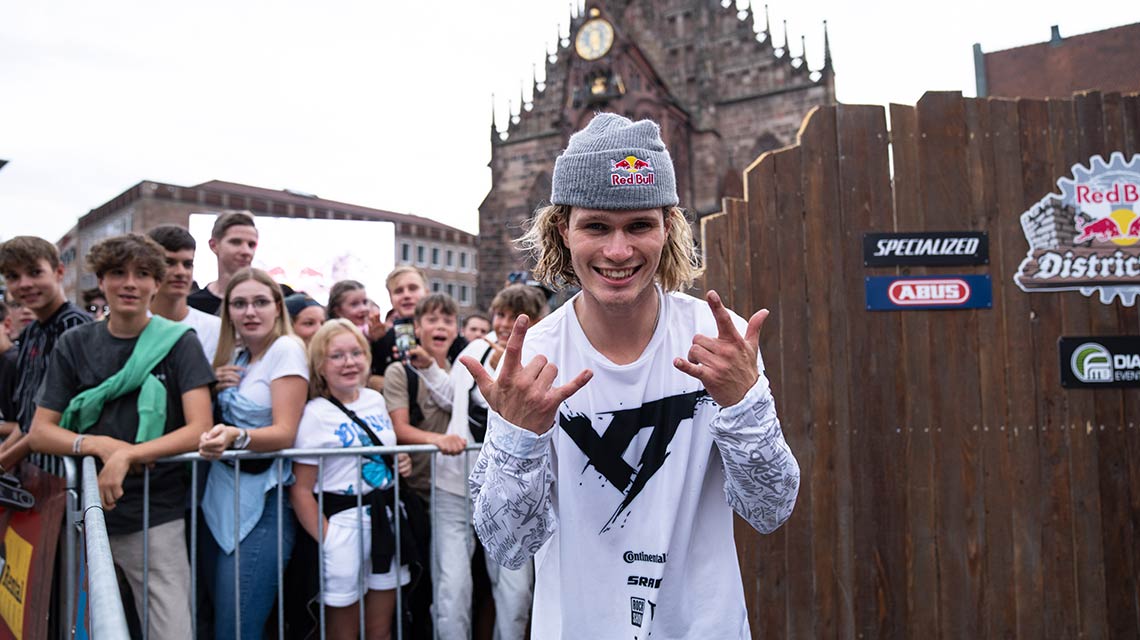 캐주얼 복장을 한 젊은 남성이 군중 앞에서 포즈를 취하고 있습니다.