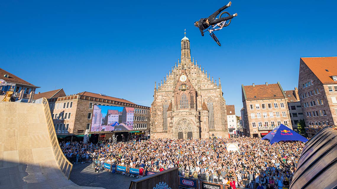 자전거 타는 사람이 큰 군중 앞에서 경사로를 넘고 있습니다.