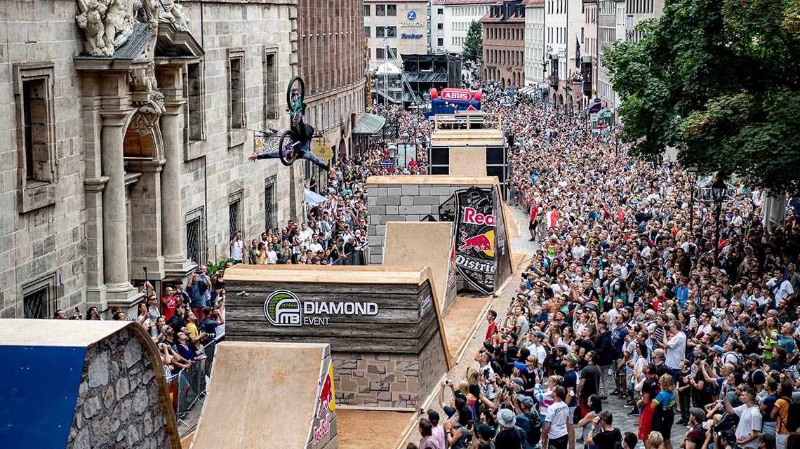 BMX 라이더가 큰 군중 앞에서 경사로를 넘고 있습니다.